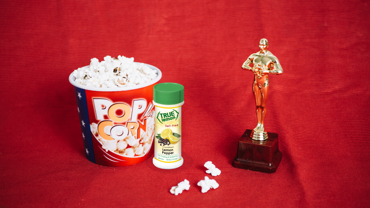An Oscar Award statue, a tub of popcorn, and True Lemon Pepper Spice Blend.