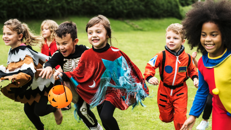 kids in Halloween costumes running on a field. 