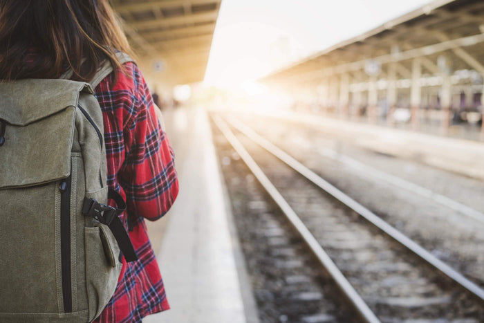 women waits for train with her backpack on