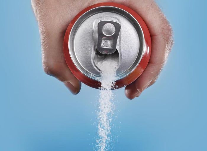a man pouring a can of soda that is filled with sugar