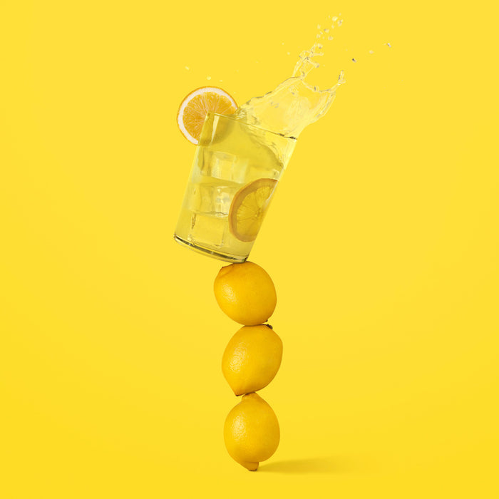 Lemons balancing on top of each other with a yellow background