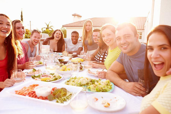 friends eat together around a large table outside