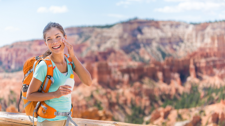 Woman at the Grand Canyon applying sunscreen. 