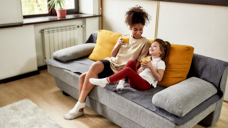 Woman sits on grey couch with daughter drinking True Lemon drink
