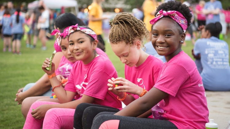 Four young girls sit down after a long run and drink True Lemon with Girls on the Run. 