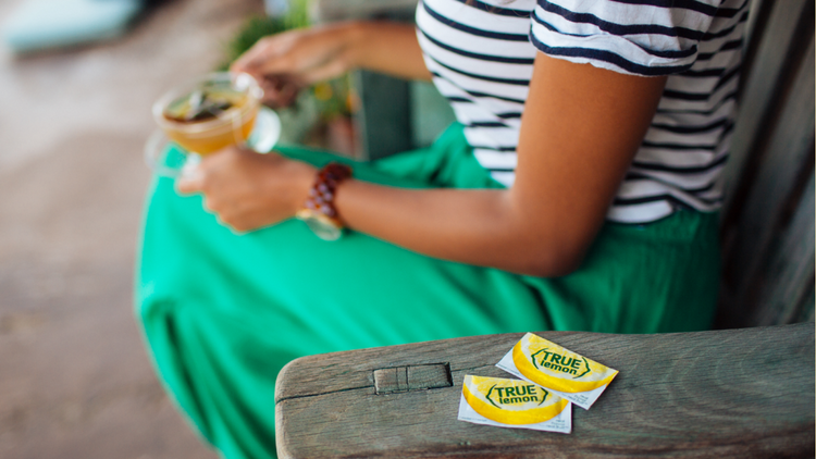 A woman sits out on her porch and drinks tea with True Lemon, which can be helpful for sore throats. 
