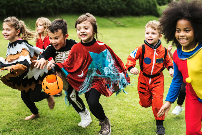 kids in Halloween costumes running on a field.
