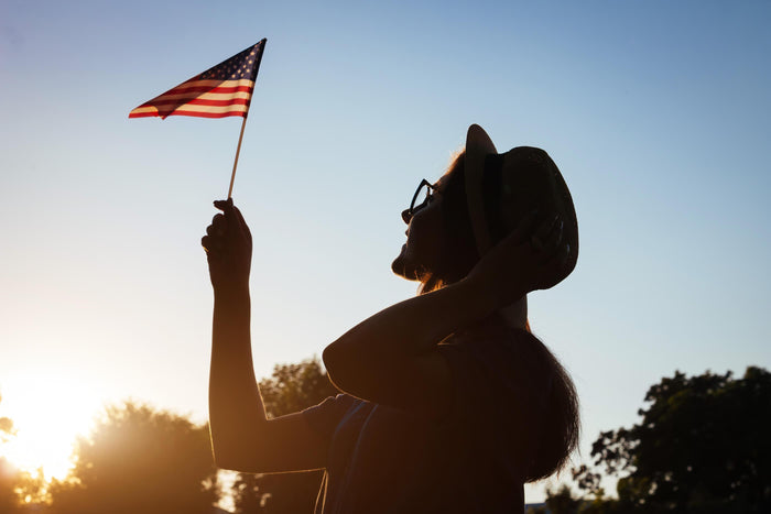 women waves an American flag at sunset