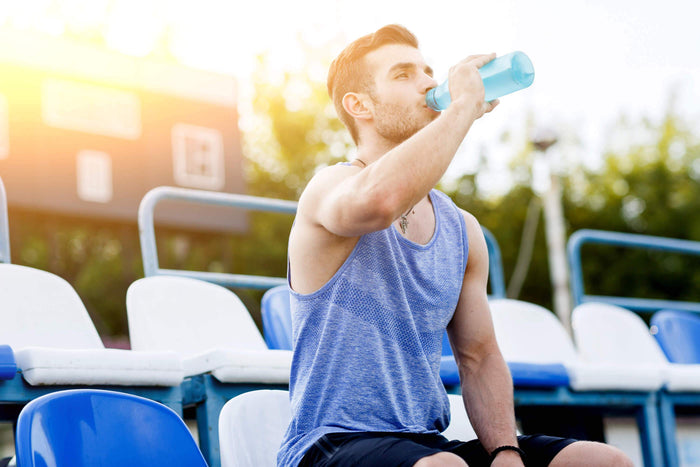 a man drinks water from a bottle after a workout