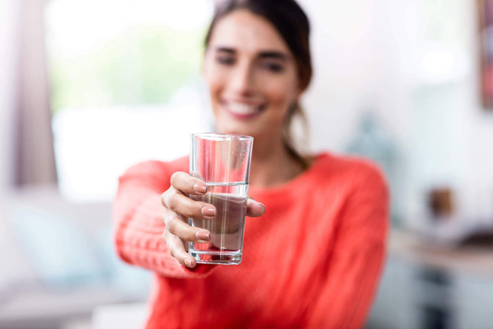 a women offers a glass of water while smiling