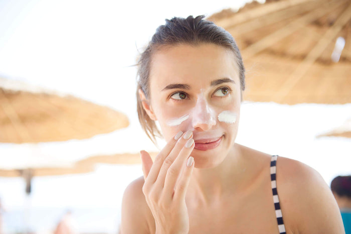 women rubs sunscreen on her face
