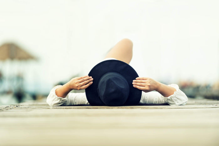 women laying on the ground with a big black hat