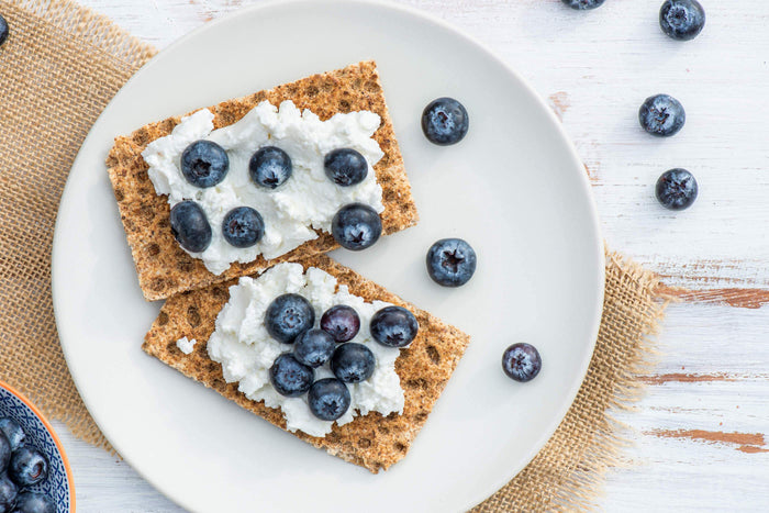crackers with cream cheese and blueberries on a plate