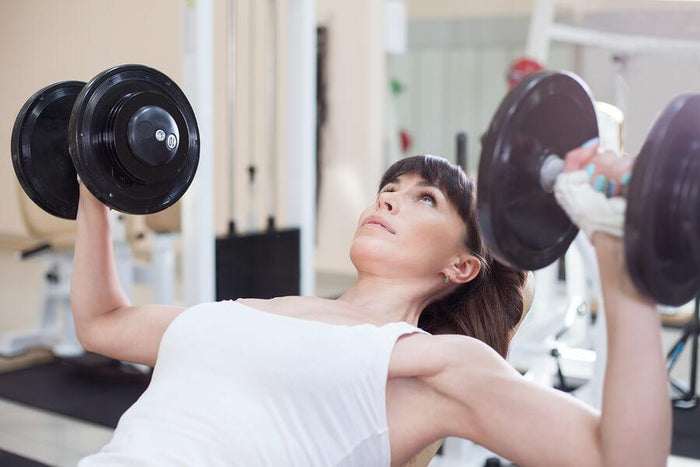 women lifts weights on a bench press