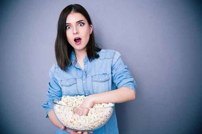 women eating popcorn out of a giant glass bowl