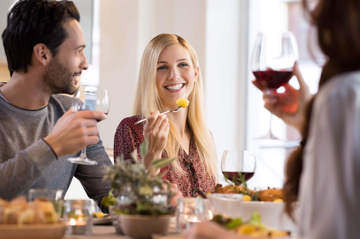 friends smile while drinking wine at dinner together