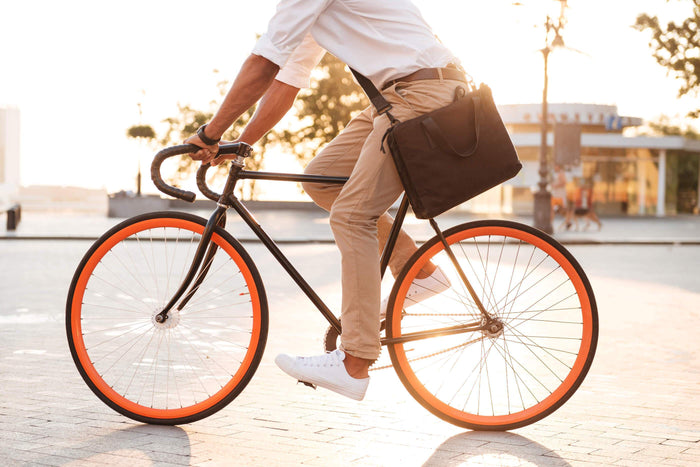 man rides bike with messenger bag