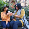Two women sit outside enjoying the autumn day and glasses of True Lemon Peach Lemonade.